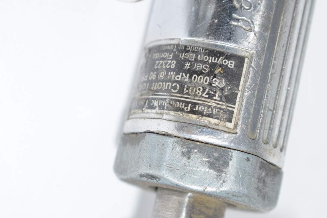 Close-up of a metal 3-inch cutoff tool showing a worn label with RPM and product details against a white background.